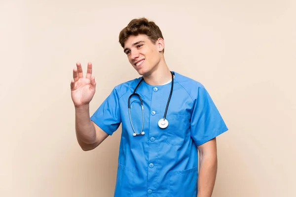 孤立した壁の上の外科医の若者は幸せな表情で手で敬礼 — ストック写真
