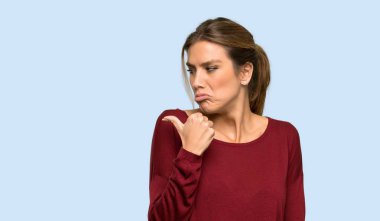 Sarışın kadın mutsuz ve izole mavi arka plan üzerinde yan işaret