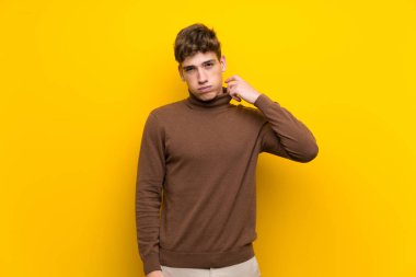 Yorgun ve hasta ifade ile izole sarı arka plan üzerinde Yakışıklı genç adam