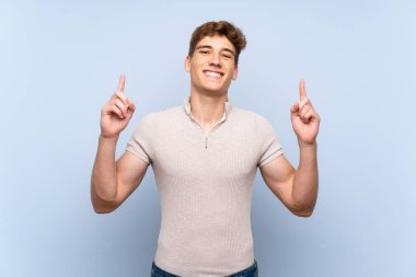 Izole mavi duvar üzerinde Yakışıklı genç adam harika bir fikir işaret