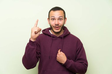 Sürpriz yüz ifadesi ile yeşil duvara Sweatshirt ile Kolombiyalı adam