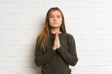 Beyaz tuğla duvar üzerinde genç kadın yalvarıyor