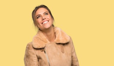 Izole sarı arka plan üzerinde gülümseyen bir ceket ile Sarışın kadın