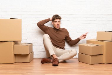 Kutular arasında yeni bir evde hareket eden yakışıklı genç adam şaşırttı ve yan parmak işaret