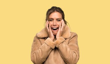 Izole sarı arka plan üzerinde ön elleri germe bir ceket sinir ve korkmuş ile Sarışın kadın