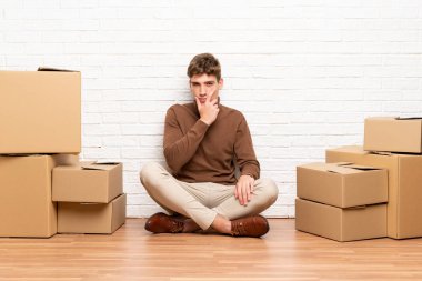 Yakışıklı genç adam kutuları arasında yeni bir evde bir fikir düşünme hareketli