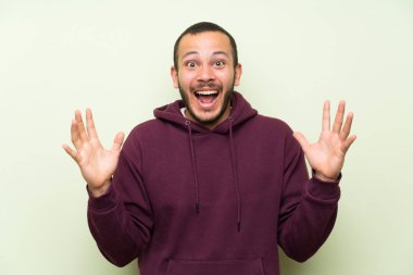 Sürpriz yüz ifadesi ile yeşil duvara Sweatshirt ile Kolombiyalı adam