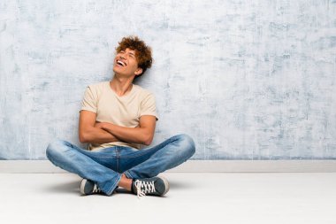 Genç afro-amerikan adam kollarını çapraz ve mutlu ile katta oturan