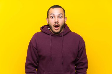Sürpriz yüz ifadesi ile sarı duvar üzerinde Sweatshirt ile Kolombiyalı adam