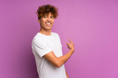 Izole mor duvar üzerinde genç afro-amerikan adam geri işaret
