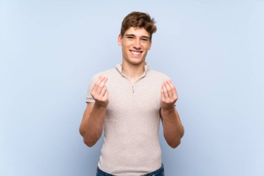 Izole mavi duvar üzerinde yakışıklı genç adam para jest yapma
