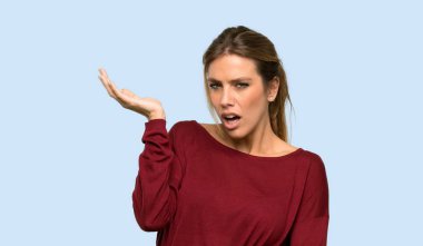 Sarışın kadın şaşırmış ve izole mavi arka plan üzerinde bakarken şok