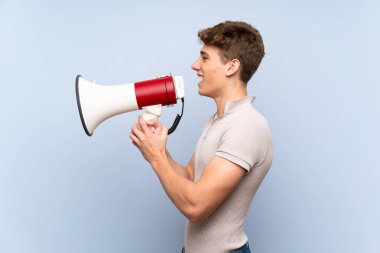 Izole mavi duvar üzerinde yakışıklı genç adam bir megafon ile bağırıyor