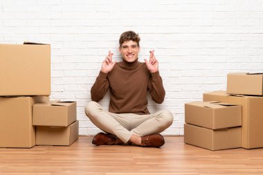 Yakışıklı genç adam parmakları geçiş ile kutular arasında yeni bir evde hareket