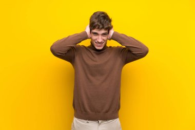 Izole sarı arka plan üzerinde Yakışıklı genç adam sinirli ve baş elleri alır