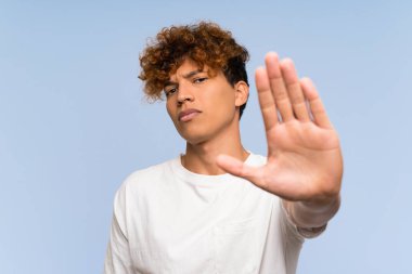 Beyaz gömlekli genç afro-amerikan adam eliyle dur jesti yapıyor