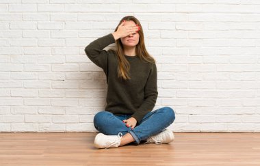 Yerde oturan genç bir kadın elleriyle gözlerini kapatıyor. Bir şey görmek istemiyorum.