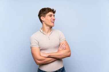 Izole mavi duvar üzerinde Yakışıklı genç adam mutlu ve gülümseyen