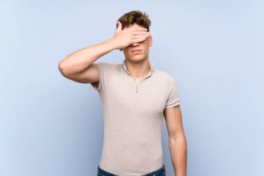 Gözleri elleriyle kaplayan izole mavi duvarın üzerinde yakışıklı genç adam. Bir şey görmek istemiyorum