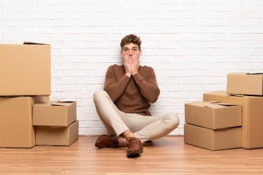 Yakışıklı genç adam sürpriz yüz ifadesi ile kutular arasında yeni evde hareket