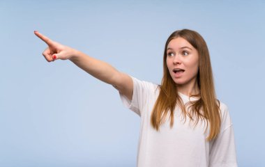 Mavi duvarın üzerinde genç kadın işaret