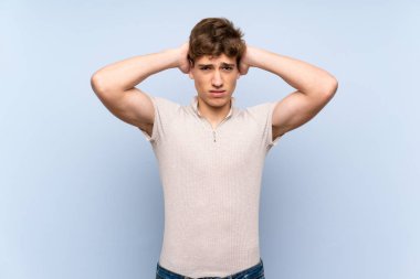 Izole mavi duvar üzerinde Yakışıklı genç adam sinirli ve baş elleri alır