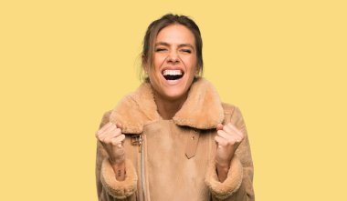 Izole sarı arka plan üzerinde ağzı geniş açık ön bağırarak bir ceket ile Sarışın kadın