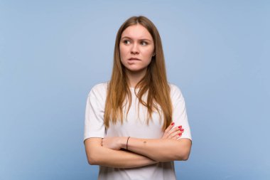 Dudaklarını ısırırken yüz ifadesi ile mavi duvar üzerinde genç kadın