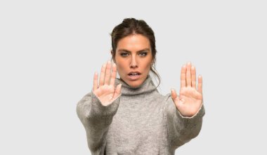 Boğazlı kazak ile Sarışın kadın stop jest yapma ve izole gri arka plan üzerinde hayal kırıklığına