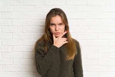 Beyaz tuğla duvar ayakta ve bir fikir düşünme üzerinde genç kadın