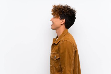 Izole beyaz duvar üzerinde genç afro-amerikan adam ayakta ve yan bakıyor