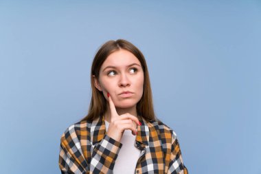 Mavi duvar üzerinde genç kadın bir fikir düşünüyor