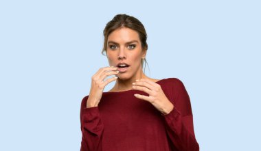 Sarışın kadın sinirli ve izole mavi arka plan üzerinde ağız adak ellerini koyarak korkmuş