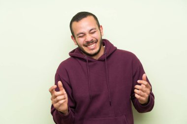 Yeşil duvara gülen Sweatshirt ile Kolombiyalı adam