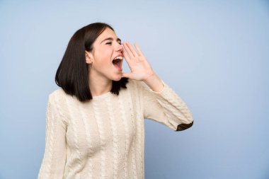 Ağzı tamamen açık bağıran izole mavi duvar üzerinde genç kadın