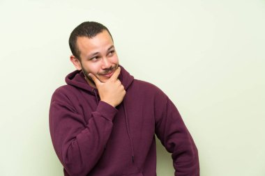 Yeşil duvar üzerinde sweatshirt ile Kolombiyalı adam bir fikir düşünme