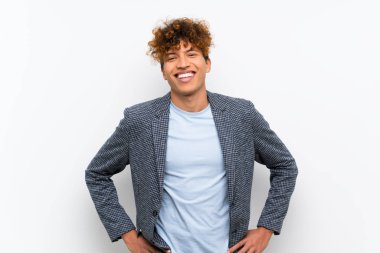 Kalça kolları ile poz izole beyaz duvar üzerinde Moda afro-amerikan adam ve gülümseyerek