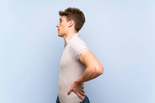 Guapo Joven Sobre Aislada Pared Azul Sufriendo Dolor Espalda Por —  Fotos de Stock