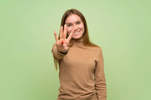 タートルネックセーターを持つ若い女性は幸せで 指で4を数える — ストック写真
