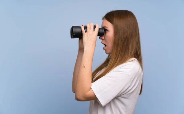 Wanita Muda Atas Dinding Biru Dan Melihat Kejauhan Dengan Teropong — Stok Foto