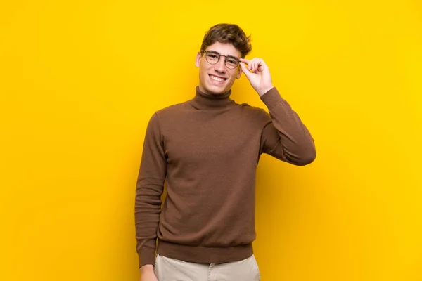 英俊的年轻人在孤立的黄色背景与眼镜和快乐 — 图库照片