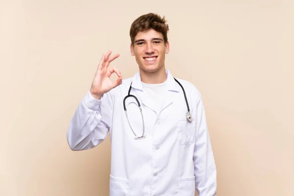 Bonito Médico Jovem Sobre Parede Isolada Mostrando Sinal Com Dedos — Fotografia de Stock