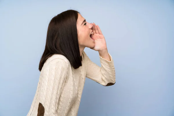 年轻女子在孤立的蓝色墙壁喊与嘴大张 — 图库照片