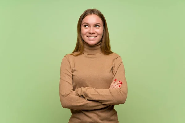 Young woman with turtleneck sweater looking up while smiling