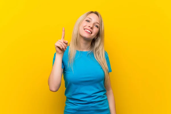 Mujer Rubia Joven Sobre Fondo Amarillo Aislado Mostrando Levantando Dedo —  Fotos de Stock