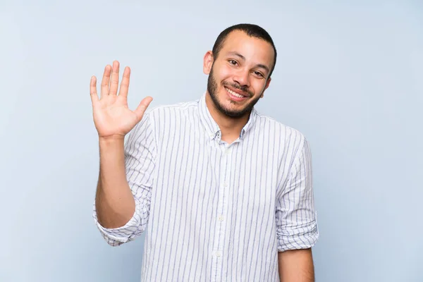 Kolumbijski Człowiek Białym Tle Niebieski Pozdrawiając Ręką Szczęśliwym Wyrazem — Zdjęcie stockowe