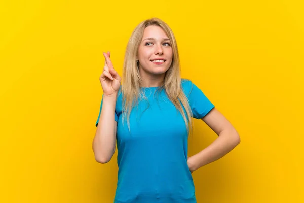 Jonge Blonde Vrouw Geïsoleerde Gele Achtergrond Met Vingers Kruisen Wensen — Stockfoto
