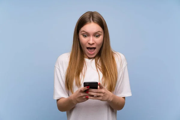 Junge Frau Über Blaue Wand Mit Handy Überrascht — Stockfoto