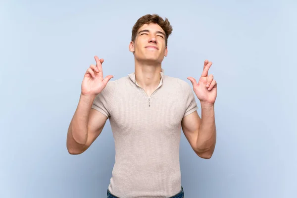 Stilig Ung Man Över Isolerad Blå Vägg Med Fingrar Korsning — Stockfoto