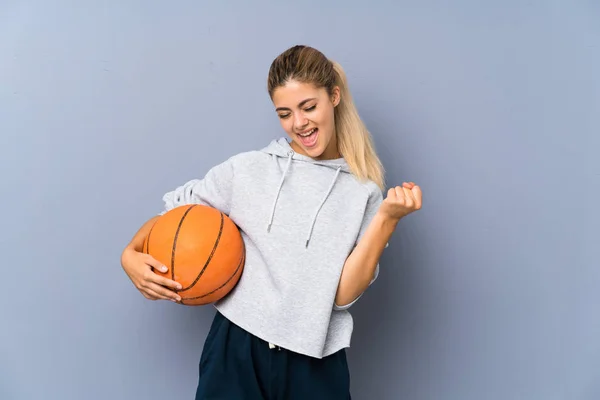 勝利を祝う灰色の壁の上にバスケットボールをしているティーンエイジャーの女の子 — ストック写真